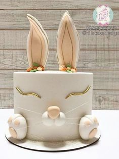 a white cake with bunny ears on it's face and two carrots sticking out of the top