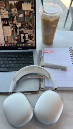 an open laptop computer sitting on top of a table next to headphones and a cup of coffee