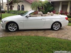 a white bmw convertible parked in front of a house