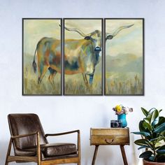 three paintings on the wall of a living room with a chair and table in front of it