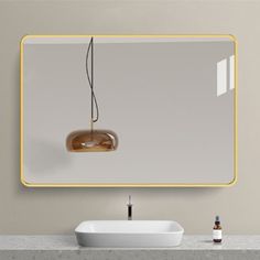 a bathroom sink sitting under a mirror next to a wall mounted faucet with a light on it