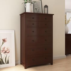 a brown dresser sitting next to a wall with pictures on top of it in a living room