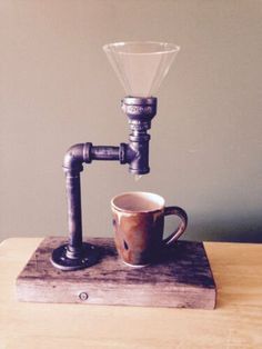 a coffee cup sitting on top of a wooden table next to a metal faucet