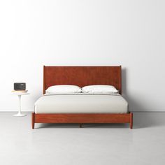 a bed with white sheets and pillows next to a night stand on concrete flooring