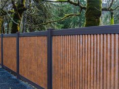 a wooden fence with metal slats on it and trees in the backround