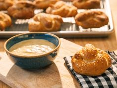 a wooden table topped with pastries next to a bowl of soup and a tray of bread