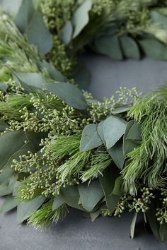 a close up of a wreath made out of leaves and greenery on a table