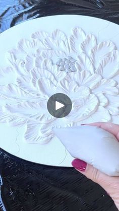 a woman is painting a flower with white paint