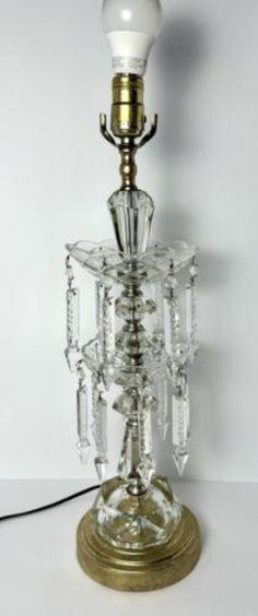 a glass table lamp with a white light bulb on it's base and some crystal beads around the base