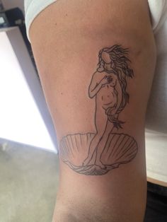 a woman with a tattoo on her arm is holding a seashell in her hand