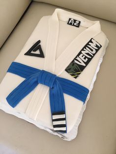 a cake made to look like a karate uniform with blue ribbon around the belt and name on it