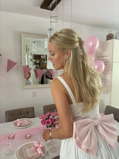 a woman standing in front of a table with pink flowers