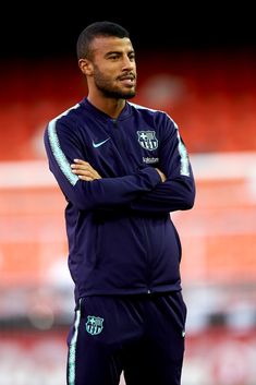 a soccer player standing on the field with his arms crossed and looking off to the side