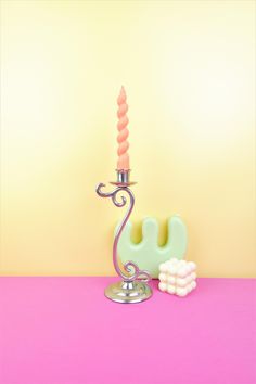 an elephant shaped candle holder next to a pink and yellow background with the word love spelled out