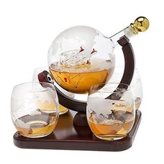 four glasses and a decanter on a wooden stand with a globe in the middle