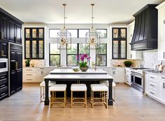 a large kitchen with black cabinets and white counter tops, along with an island in the middle