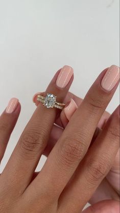 a woman's hand holding a ring with a diamond on it and two fingers