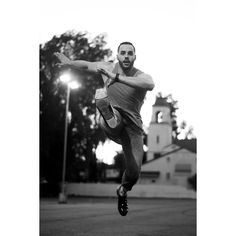 a man is jumping in the air with his arms out to catch a frisbee