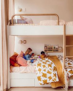 two children are sitting on the bottom bunk of their bed, reading books and having fun