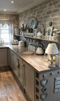 a kitchen filled with lots of counter top space and wooden flooring next to a brick wall