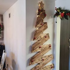 a christmas tree made out of wooden planks hanging on the side of a wall