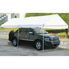 a black truck parked under a white tent on the side of a road in front of a building