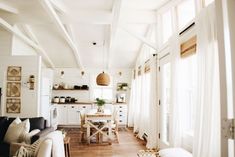 a living room filled with furniture next to a kitchen and dining room table on top of a hard wood floor