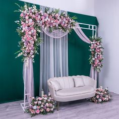 a white couch sitting under a pink flower covered arch on top of a wooden floor