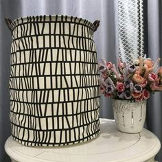 a vase with flowers sitting on top of a white table next to a black and white basket