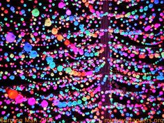 colorful lights in the shape of a tree are lit up with multicolored balls