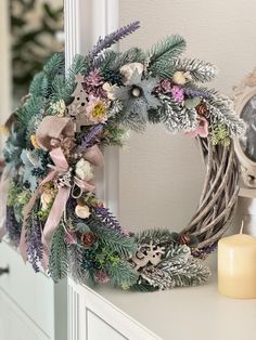 a wreath is sitting on top of a dresser next to a clock and candlestick