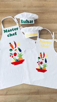 two aprons with different designs on them sitting on a wooden table next to each other