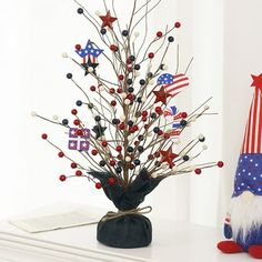 a small christmas tree with red, white and blue decorations on it next to an american flag hat