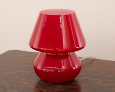 a red vase sitting on top of a wooden table