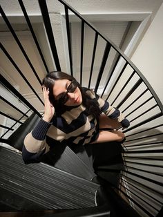 a woman standing on the top of a spiral stair case holding her hands to her head