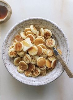 a bowl filled with sliced bananas and butter on top of a table next to a cup