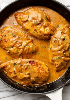 chicken with gravy in a skillet on a marble counter top, ready to be eaten