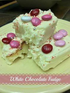 two pieces of white chocolate fudge cake on a yellow plate with pink and red candies