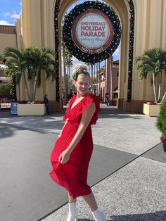 a woman in a red dress posing for the camera at universal studios's entrance