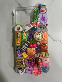 a cell phone case with many different items on the front and back cover, sitting on a marble surface