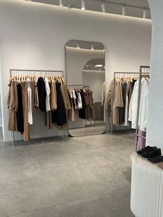 a clothing store with clothes hanging on racks and mirrors in front of the wall,