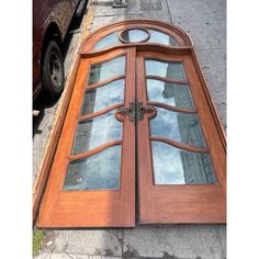 an old wooden door with glass on the side walk next to a truck and sidewalk