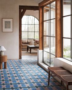 a living room filled with furniture and windows next to a blue rug on the floor