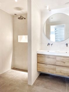 a bathroom with two sinks and a large round mirror on the wall above it's counter