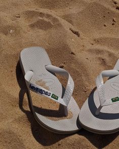 a pair of white flip flops sitting in the sand