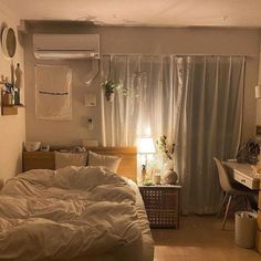 an unmade bed sitting in a bedroom next to a desk with a lamp on it