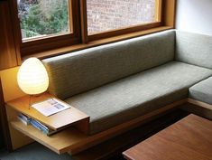 a corner couch with a lamp on it next to a window