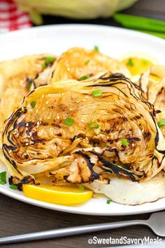 a white plate topped with artichoke and lemon wedges next to a fork