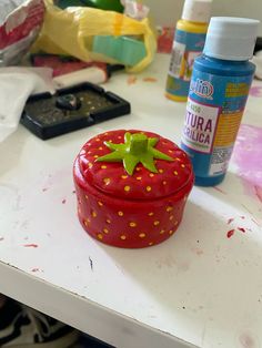 a strawberry shaped container sitting on top of a table next to other crafting supplies