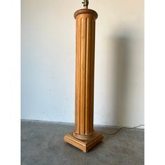 a tall wooden lamp on top of a cement floor